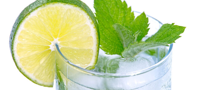 glass of ice water with a slice of lime and some mint leaves